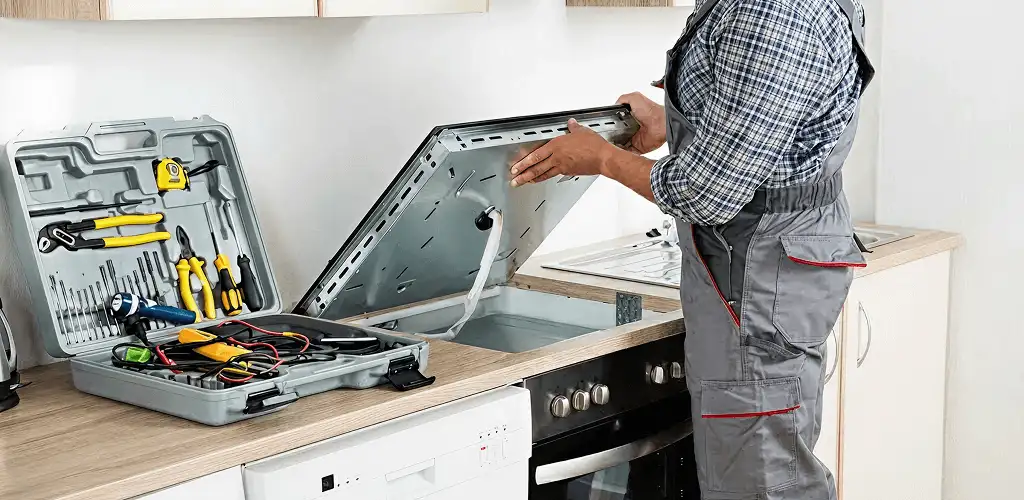 Handyman repairing a cooktop and checking wiring connections in Overland Park, KS