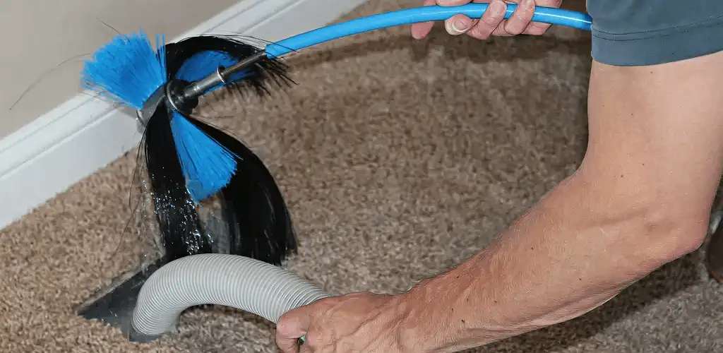 Dryer vent cleaning technician brushing lint from a vent line in Overland Park, KS