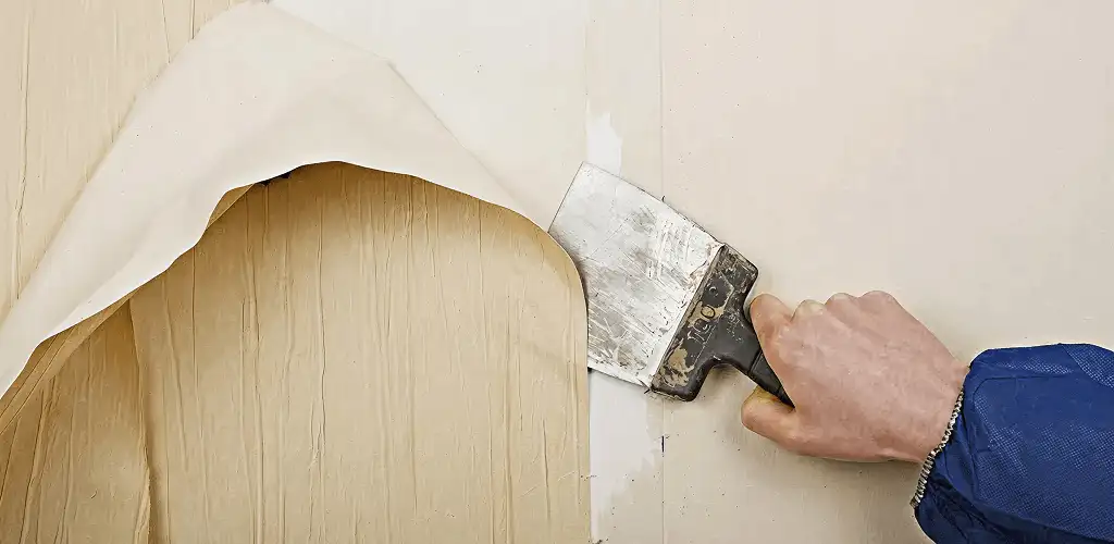 Handyman removing wallpaper with a scraper for wall preparation in Overland Park, KS
