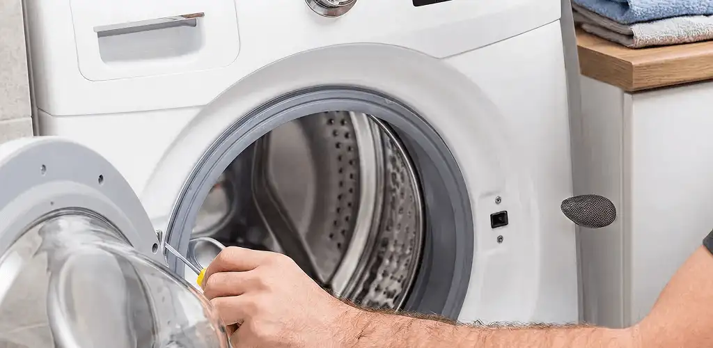 Handyman repairing a front-load washing machine and inspecting the drum in Overland Park, KS