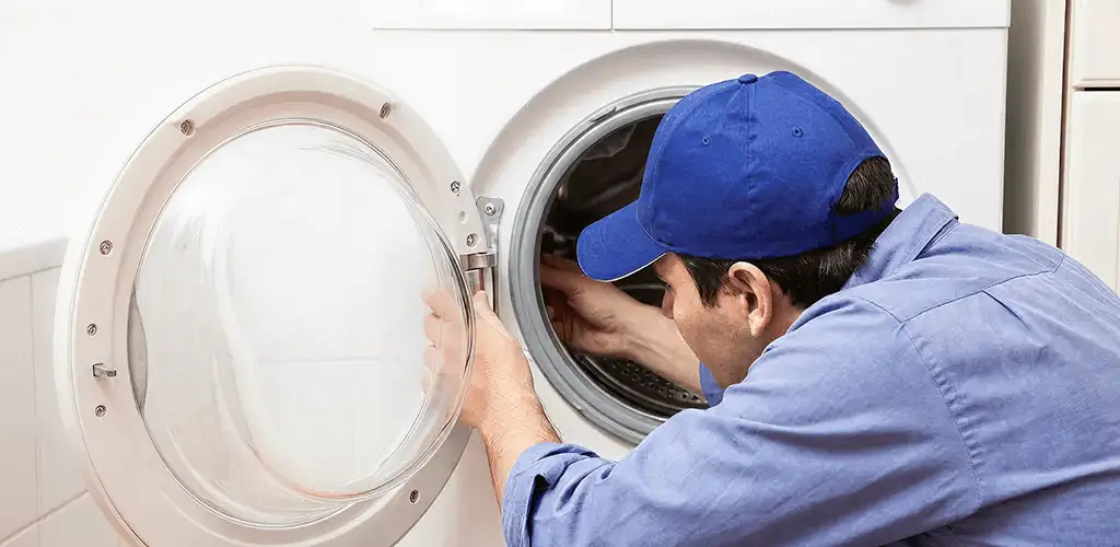 Washing machine repair handyman inspecting a front-load washer drum in Overland Park, KS