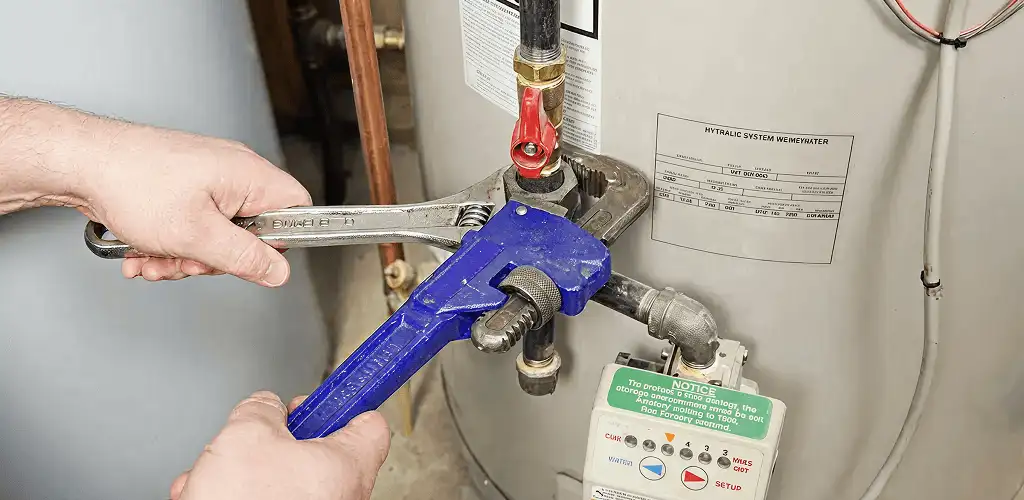 Water heater repair technician tightening the shutoff valve and supply line in Overland Park, KS